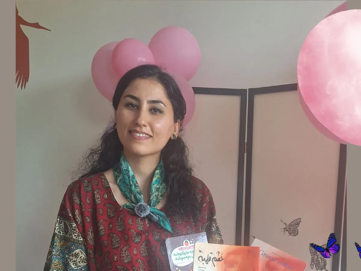 Une Persane, entourée de ballons roses, présente des livres en perse.