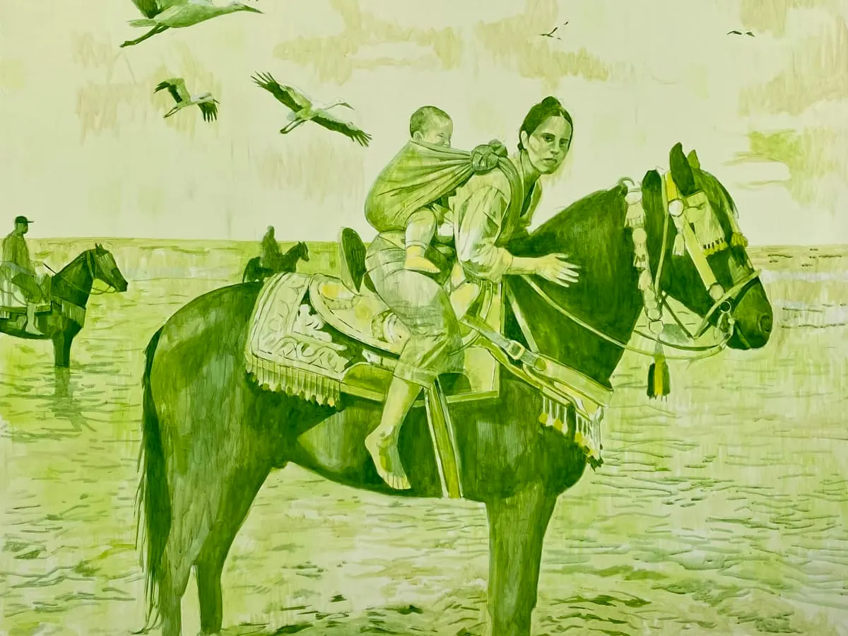 Une femme porte son bébé au dos tout en étant assise sur un cheval.