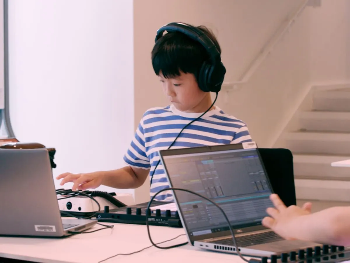 Un jeune pré-ado utilise un logiciel de création musicale sur un ordinateur.