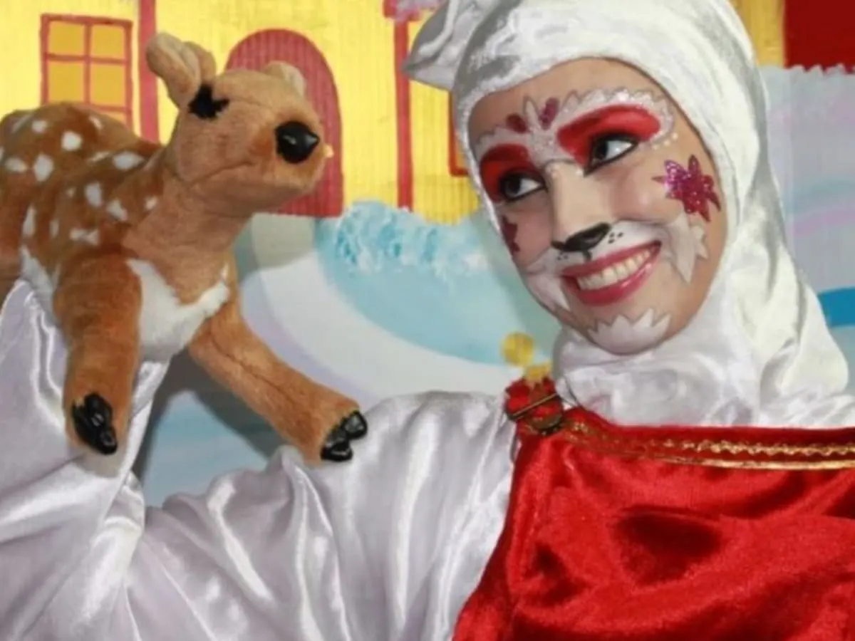 Une personne déguisé en chat tient une marionnette d'une biche dans sa main