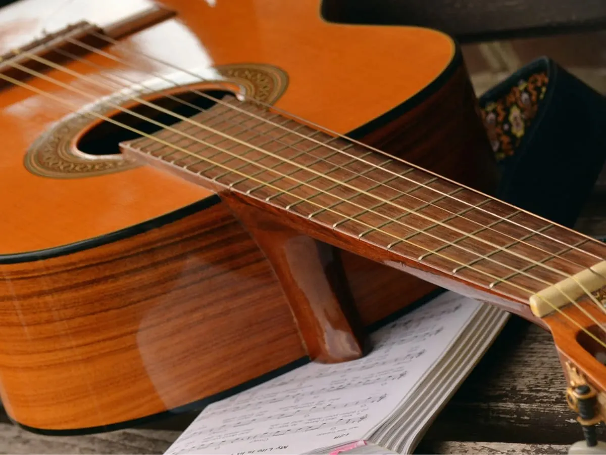 Une photographie d'une guitare déposée sur une partition imprimée.