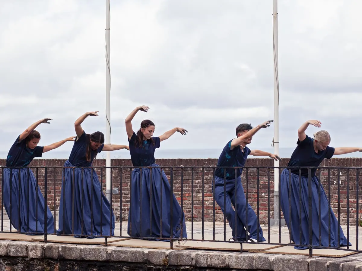 5 personnes vêtues de bleu qui danse dehors sur un quai
