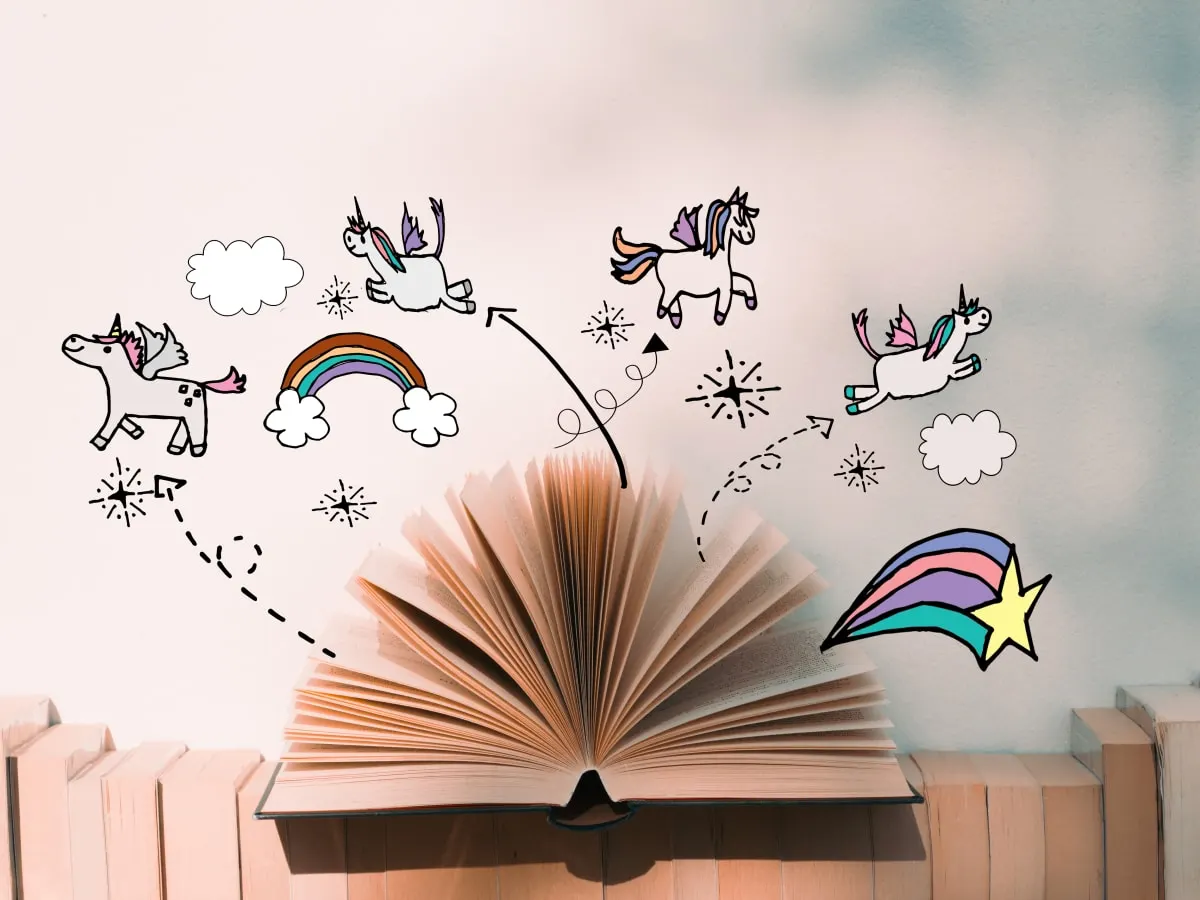 Livre ouvert avec dessins de licornes au dessus de celui-ci.