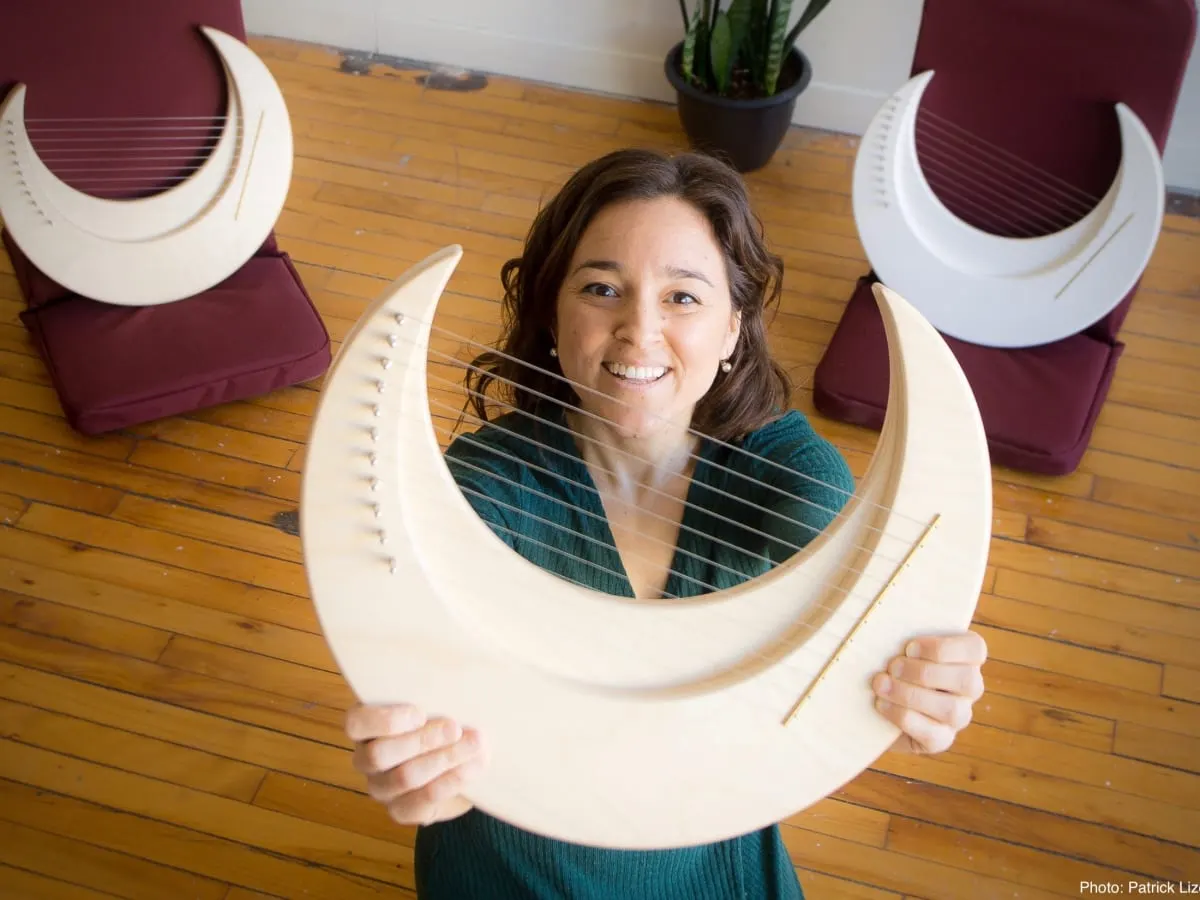 Une personne tien dans ses mains une harpe-lyre fabriquée au Québec.