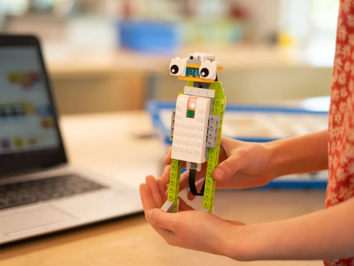 Un enfant tient dans ses mains un petit robot construi en pièces de LEGO
